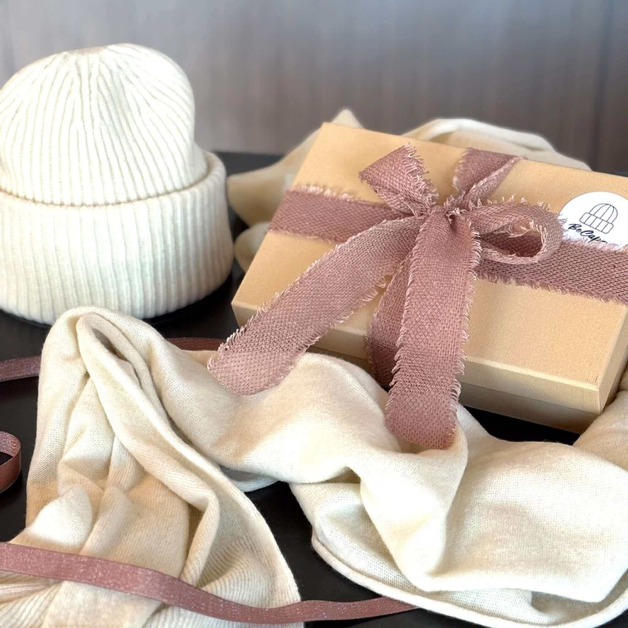 Gift Card di pura eleganza presented in a stylish package with a beige scarf and cream beanie.