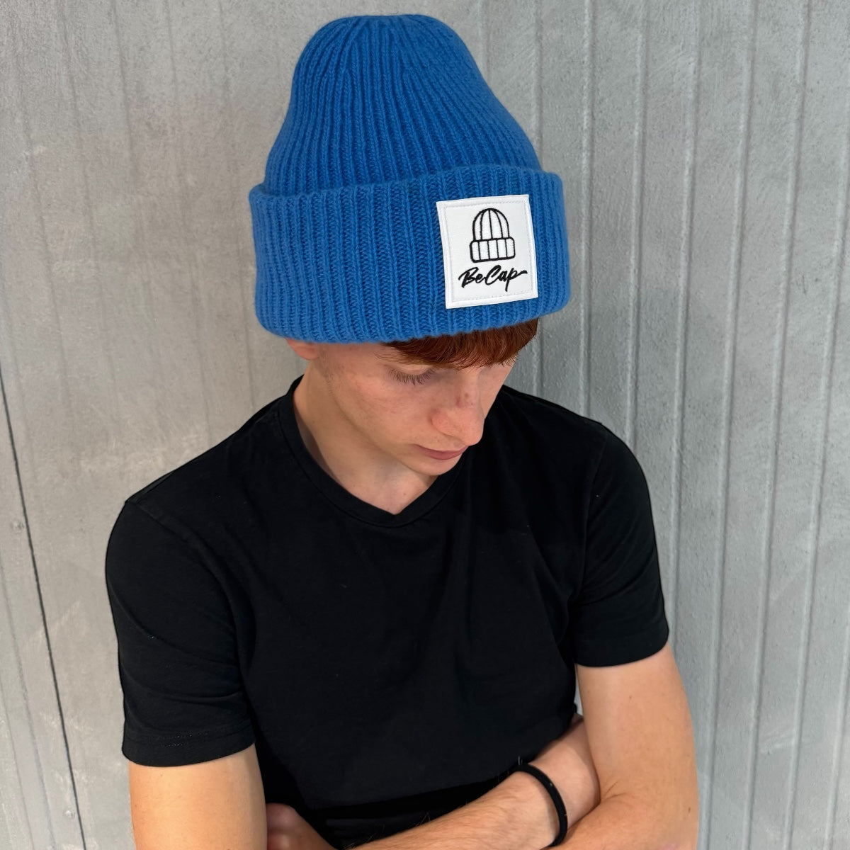 CUFFIA OVER 100% LANA MERINO LOGO BECAP FIORDALISO indossata da giovane in maglione nero.