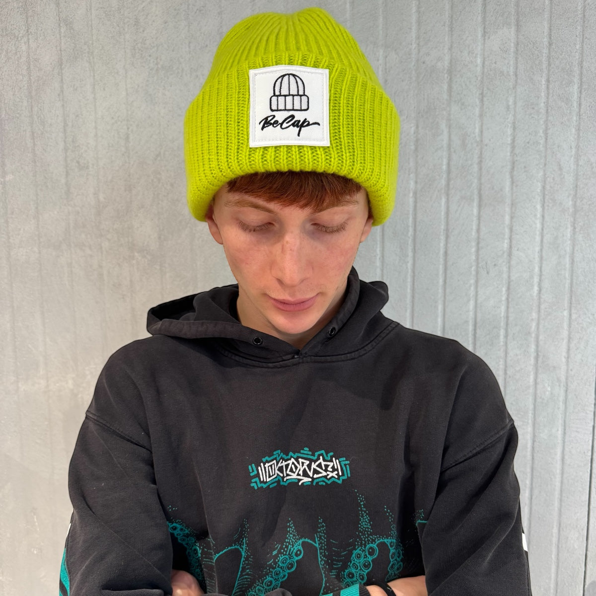 Cuffia lana merino unisex BeCap in colore neon indossata da giovane con maglione scuro.